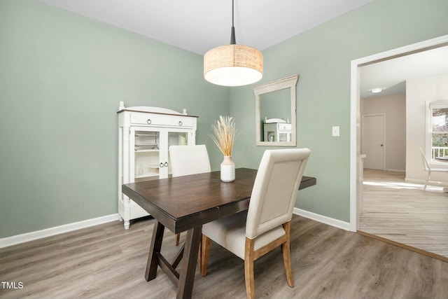 dining area with light wood-type flooring and baseboards