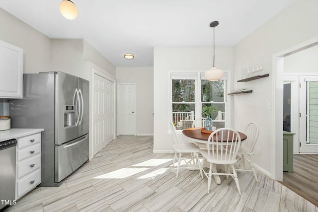 kitchen with appliances with stainless steel finishes, white cabinets, light countertops, and decorative light fixtures