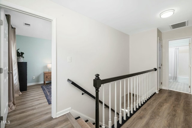 staircase with baseboards, visible vents, and wood finished floors