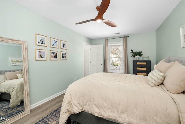 bedroom with a ceiling fan, visible vents, baseboards, and wood finished floors