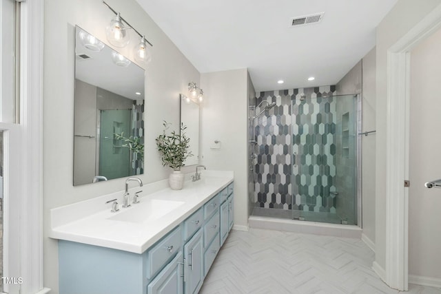 bathroom featuring double vanity, a stall shower, a sink, and visible vents