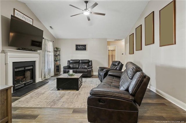 living area with a fireplace with raised hearth, wood finished floors, visible vents, and lofted ceiling