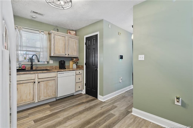 kitchen featuring white appliances, light brown cabinets, visible vents, and a sink