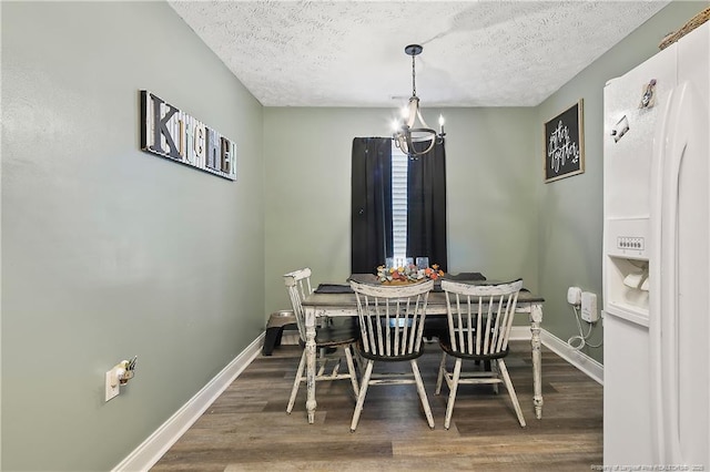 dining space featuring baseboards, a textured ceiling, a chandelier, and wood finished floors