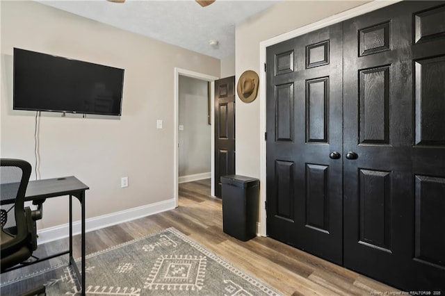 home office with baseboards and wood finished floors