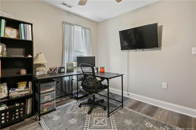 home office featuring baseboards, dark wood-style flooring, visible vents, and a ceiling fan