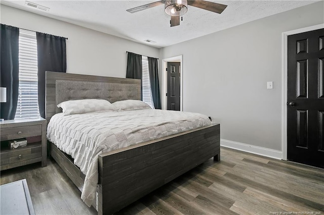 bedroom featuring baseboards, visible vents, dark wood finished floors, and a textured ceiling