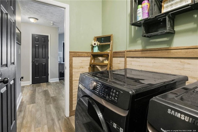 clothes washing area featuring washer and dryer, a textured ceiling, and wood finished floors