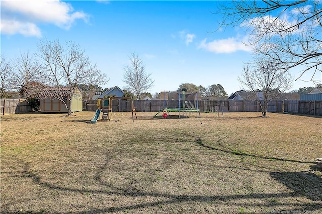 view of jungle gym with a yard, a shed, a trampoline, and a fenced backyard