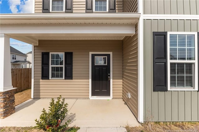 property entrance with board and batten siding and fence