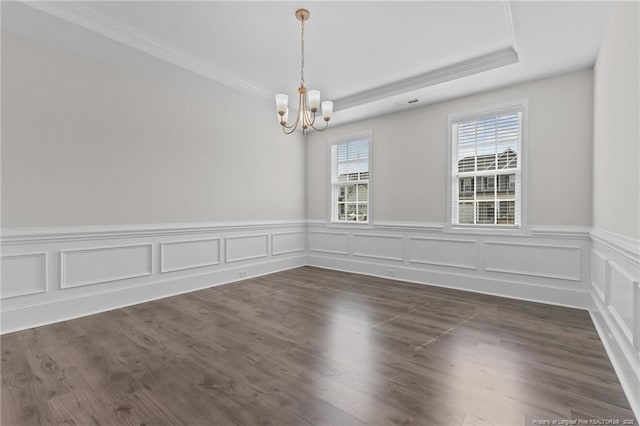 spare room with a chandelier, a raised ceiling, dark wood-type flooring, and crown molding