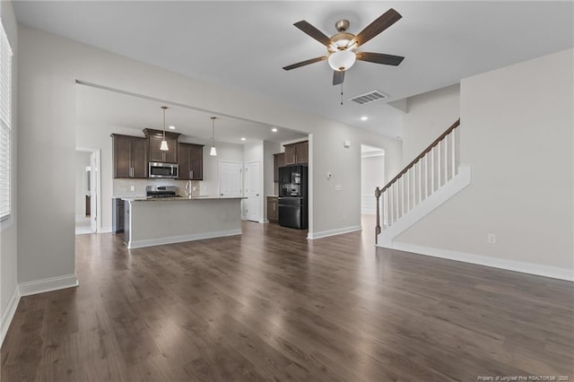 unfurnished living room with dark wood finished floors, visible vents, stairway, ceiling fan, and baseboards