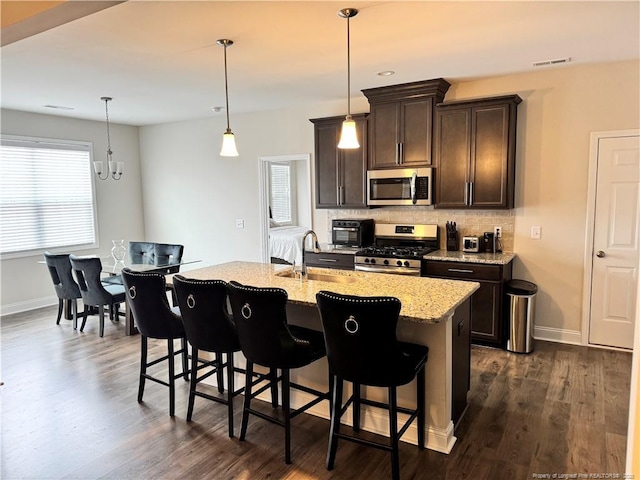 kitchen featuring tasteful backsplash, appliances with stainless steel finishes, dark wood-type flooring, dark brown cabinets, and a sink