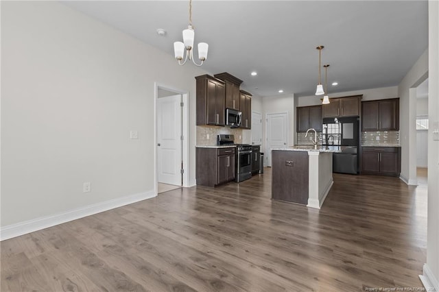 kitchen with stainless steel appliances, dark wood-style flooring, dark brown cabinetry, and open floor plan