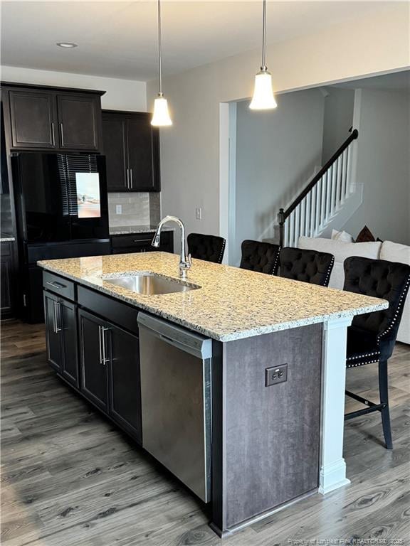 kitchen featuring stainless steel dishwasher, light wood-style floors, freestanding refrigerator, a sink, and a kitchen breakfast bar