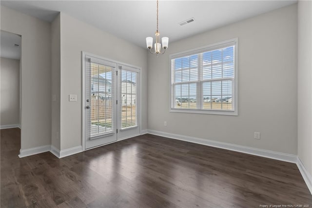 unfurnished dining area with dark wood-style flooring, visible vents, a notable chandelier, and baseboards