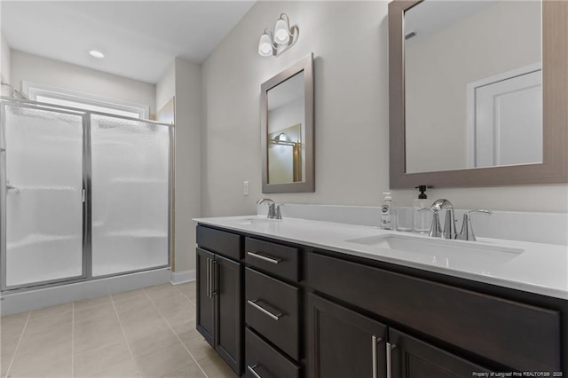 bathroom with double vanity, a stall shower, a sink, and tile patterned floors