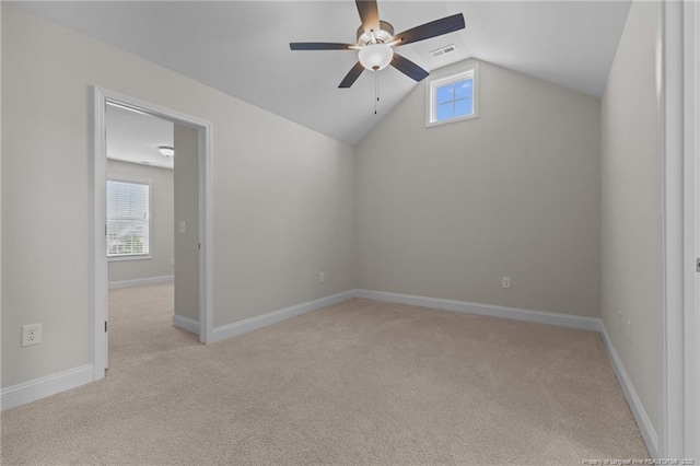 empty room with lofted ceiling, light carpet, visible vents, and baseboards