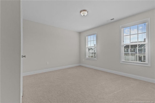 unfurnished room featuring carpet, visible vents, and baseboards