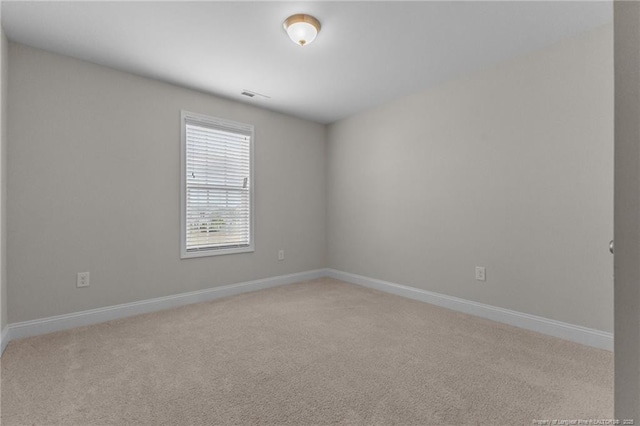 empty room featuring light carpet, visible vents, and baseboards