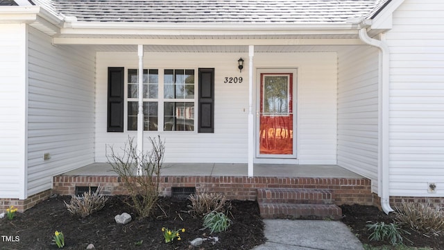 doorway to property with a porch, crawl space, and a shingled roof