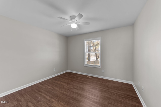 empty room with a ceiling fan, dark wood-style flooring, visible vents, and baseboards