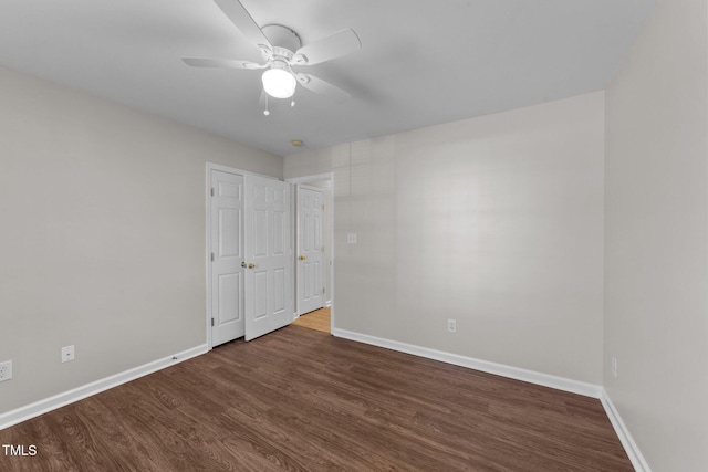 empty room with dark wood-type flooring, baseboards, and a ceiling fan