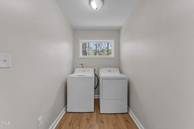 laundry area with laundry area, baseboards, light wood-style flooring, and washing machine and clothes dryer