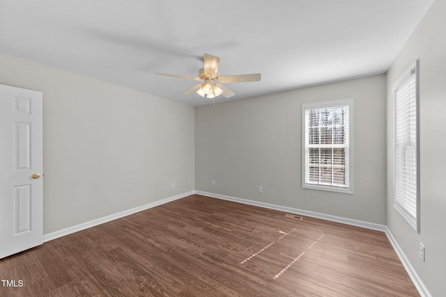 unfurnished room featuring visible vents, wood finished floors, a ceiling fan, and baseboards