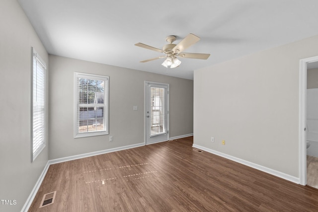 unfurnished room with wood finished floors, visible vents, and baseboards