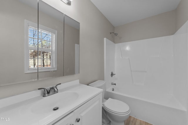 full bathroom featuring wood finished floors, shower / washtub combination, vanity, and toilet