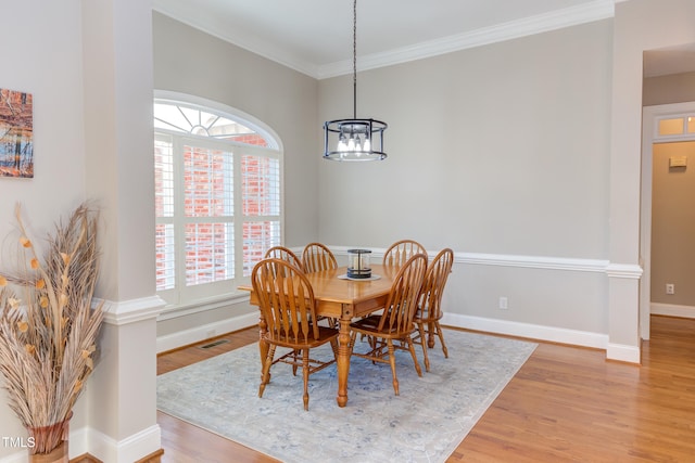 dining room with crown molding, a notable chandelier, baseboards, and light wood-type flooring