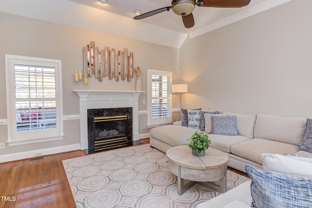 living room featuring baseboards, ceiling fan, vaulted ceiling, a fireplace, and wood finished floors