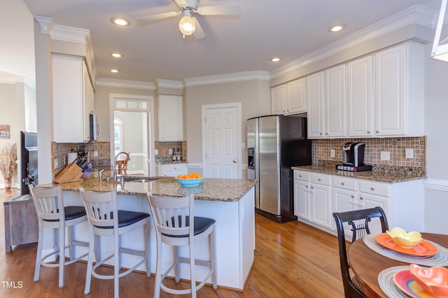 kitchen featuring light wood-style flooring, a ceiling fan, a sink, stainless steel appliances, and a peninsula