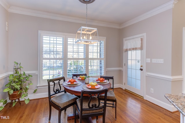 dining space featuring baseboards, a notable chandelier, ornamental molding, and light wood finished floors