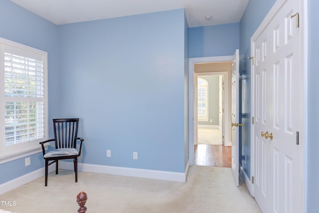 sitting room with light carpet, a healthy amount of sunlight, and baseboards