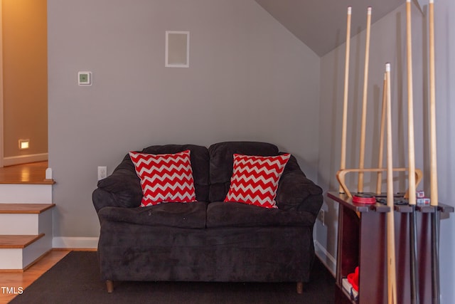 living area featuring vaulted ceiling, wood finished floors, and baseboards