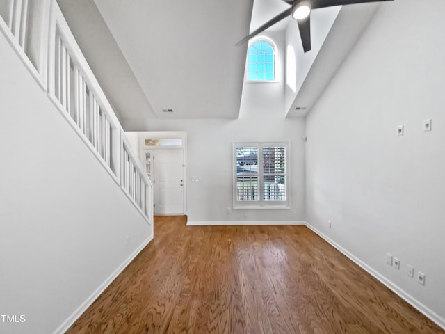 unfurnished living room featuring ceiling fan, wood finished floors, visible vents, baseboards, and stairway