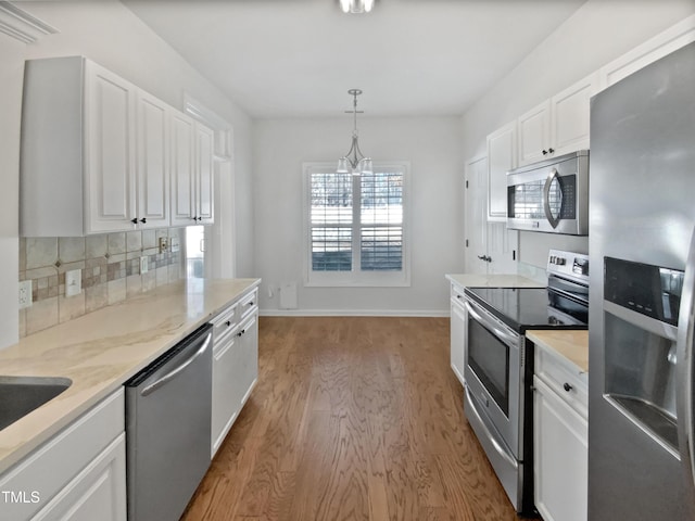 kitchen with decorative backsplash, light wood-style flooring, hanging light fixtures, stainless steel appliances, and white cabinetry