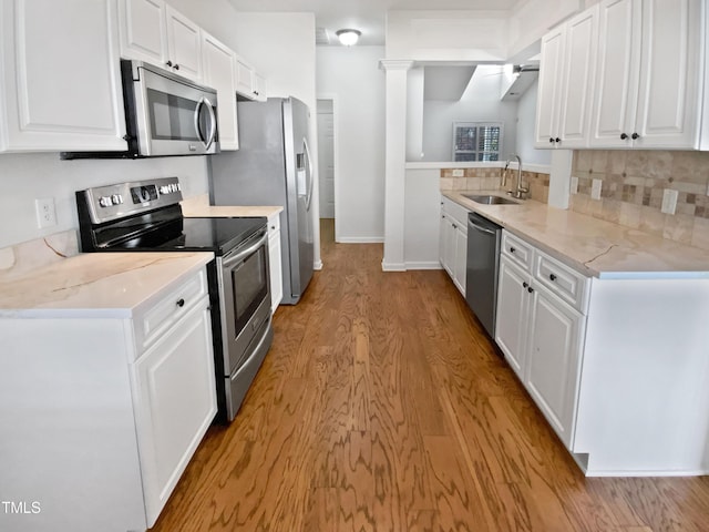 kitchen with light wood-style flooring, a sink, white cabinets, appliances with stainless steel finishes, and light stone countertops