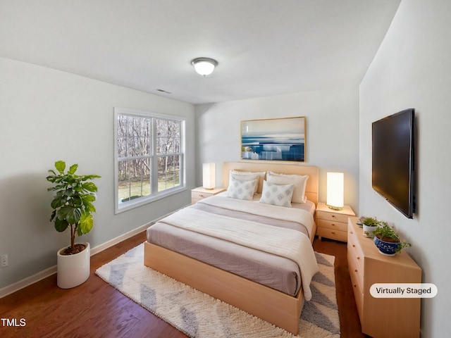 bedroom with wood finished floors, visible vents, and baseboards