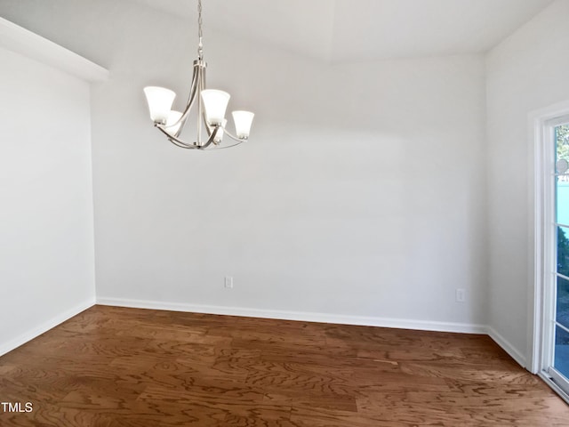 spare room with a notable chandelier, baseboards, and dark wood-type flooring