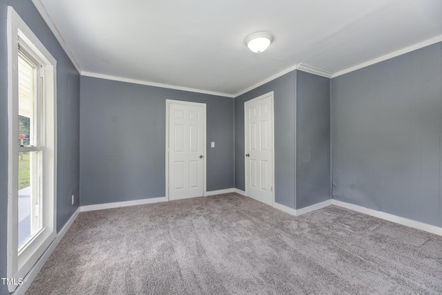 empty room with carpet, ornamental molding, and baseboards