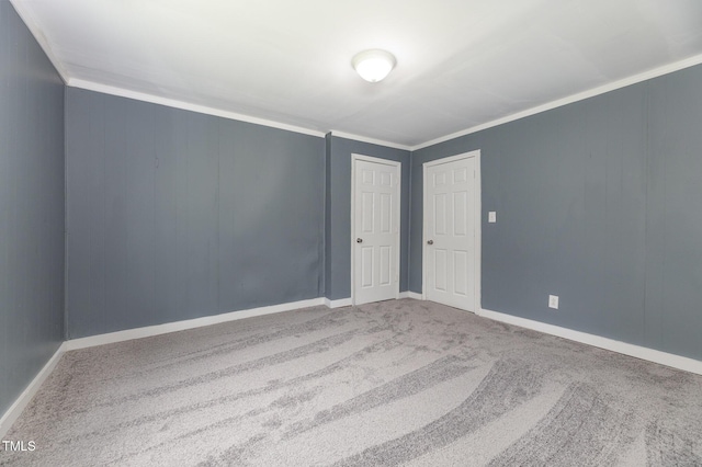 empty room featuring carpet floors, baseboards, and crown molding