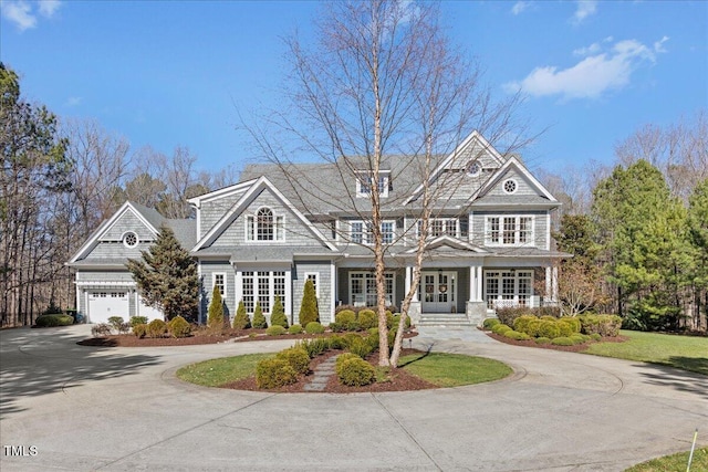 shingle-style home featuring covered porch, curved driveway, and french doors