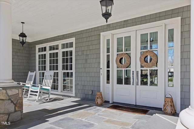 view of exterior entry with a porch and french doors