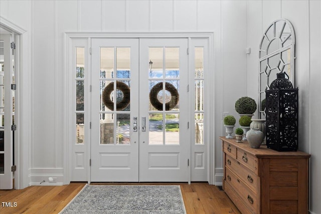 doorway to outside featuring french doors, a decorative wall, and light wood-style floors