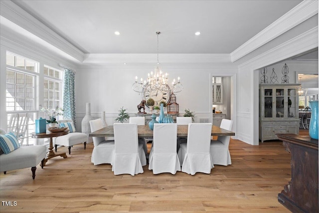 dining area with a raised ceiling, an inviting chandelier, crown molding, light wood-style floors, and recessed lighting