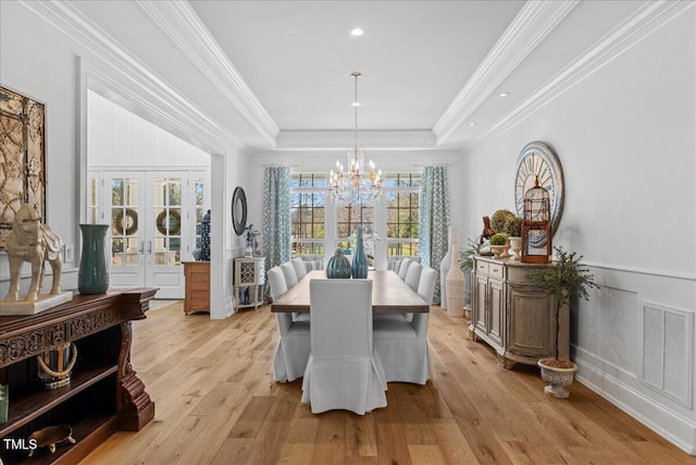 dining space featuring french doors, crown molding, a raised ceiling, visible vents, and light wood-type flooring