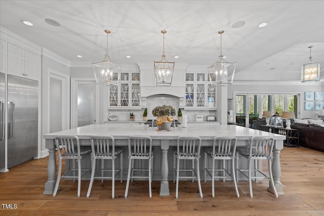 kitchen featuring decorative backsplash, white cabinetry, light wood finished floors, and built in refrigerator